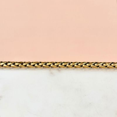 a close up of a gold chain on a marble surface