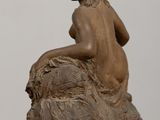 statue of a woman sitting on a rock on a table