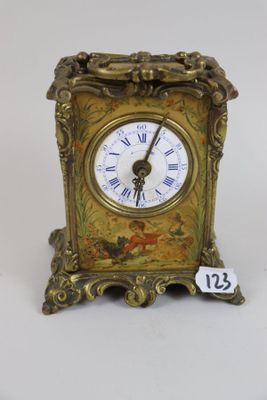 a small gold clock with roman numerals on it