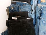several pairs of jeans are stacked on top of each other