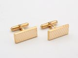 a pair of gold cufflinks on a white background