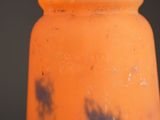 a close up of a orange vase with black spots on it