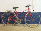 un vélo rouge appuyé contre un mur bleu et blanc