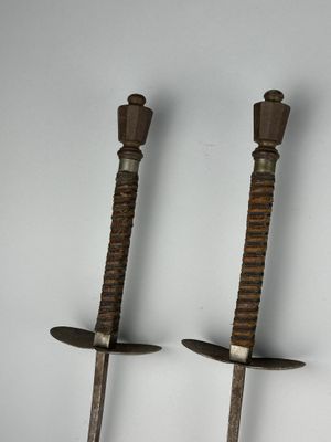 une paire d'épées anciennes en bois avec des poignées en métal, sur fond blanc