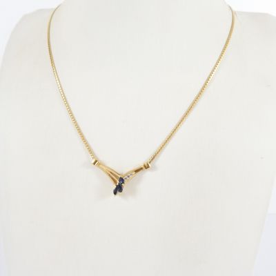 un collier en or orné de deux pierres bleues autour du cou d'un mannequin