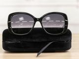 sunglasses on a black case on a wooden table with a white wall in the background