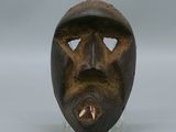 une image représentant un masque en bois posé sur un socle transparent