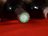 several bottles of wine are lined up on a red cloth