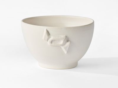a white bowl with a bird on it on a white surface