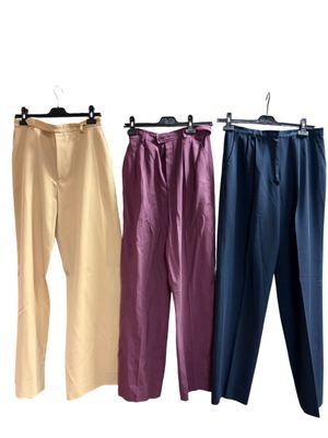 trois paires de pantalons suspendues à un portant, sur fond blanc