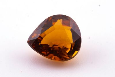 un gros plan d'un diamant brun à facettes posé sur une surface blanche