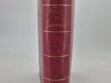 an old red book with gold trim sitting on a white surface