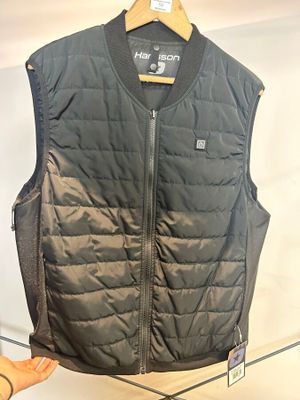 Dans une pièce, quelqu'un tient un gilet noir accroché à un cintre.