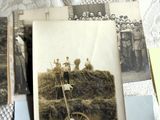 une pile de vieilles photos posée sur un lit recouvert d'une couette blanche