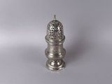 an antique silver salt shaker sitting on a white surface