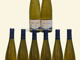 six bottles of white wine are arranged in a pyramid on a white surface