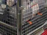many bags of luggage sitting in a metal cage