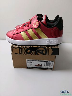 Les baskets Adidas rouges et dorées sont posées sur une boîte en carton
