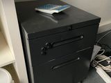a black filing cabinet with a remote control on top of it