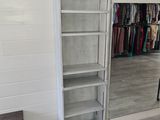 a closet in the corner of a room with clothes on the shelves