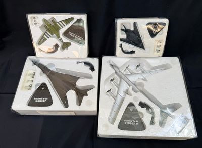 trois boîtes contenant un assortiment de maquettes d'avions, posées sur une surface noire