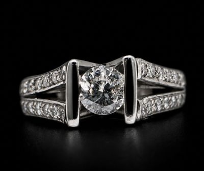 a close up of a diamond ring on a black surface