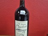a bottle of wine sitting on a table in front of a red wall