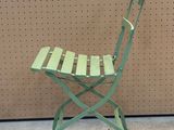 a green folding chair that is sitting on the floor