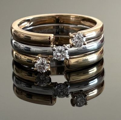 deux bagues en or et en argent, ornées de diamants, posées sur une surface réfléchissante