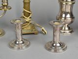 three silver candles on a table with a clock in the background
