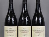 three bottles of red wine sit on a glass table