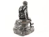 statue of a man sitting on a rock with his back to the camera