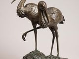 bronze statue of two birds standing on a rock on a white background