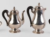 trois théières en argent et deux tasses en argent posées sur une table
