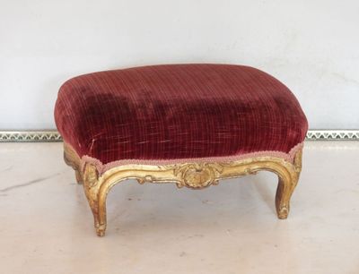 un pouf rouge et doré posé sur un sol blanc