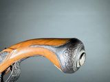 a close up of a gun with a wooden handle on a gray background