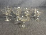 six verres à pied sont alignés sur une table