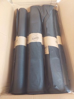 trois rouleaux de tissu noir dans une boîte en carton sur laquelle sont apposées des étiquettes