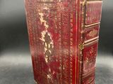 an old red book sitting on top of a table