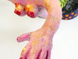 une statue représentant une personne dont les mains sont peintes, posée sur une table
