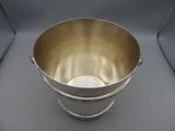 an antique silver plated bucket with rope handles on a grey background