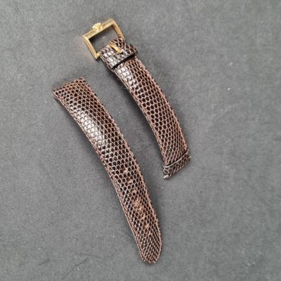 a close up of two brown snakeskin watch straps on a gray surface