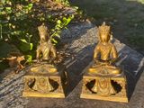 two statues of buddhas sitting on a table
