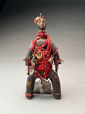 statue d'un homme assis sur un rocher, avec un cordon rouge autour du cou