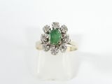 a close up of a ring with a green stone surrounded by white diamonds