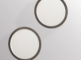 two round mirrors on a wall with a white background