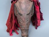 un vieux masque en bois avec un foulard rouge autour du cou