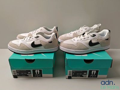 two pairs of white and black sneakers are sitting on top of a box