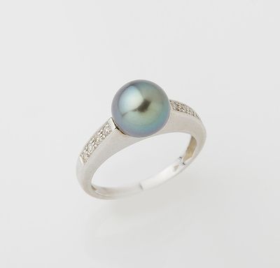a black pearl and diamond ring on a white background