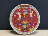 une assiette rouge sur laquelle sont représentés des anges et une horloge